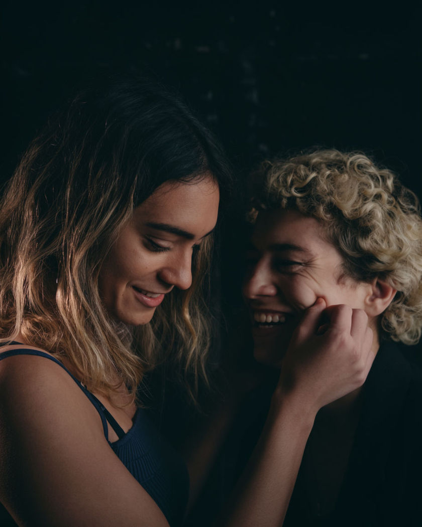 One person gently pinching another’s cheek as both laugh together