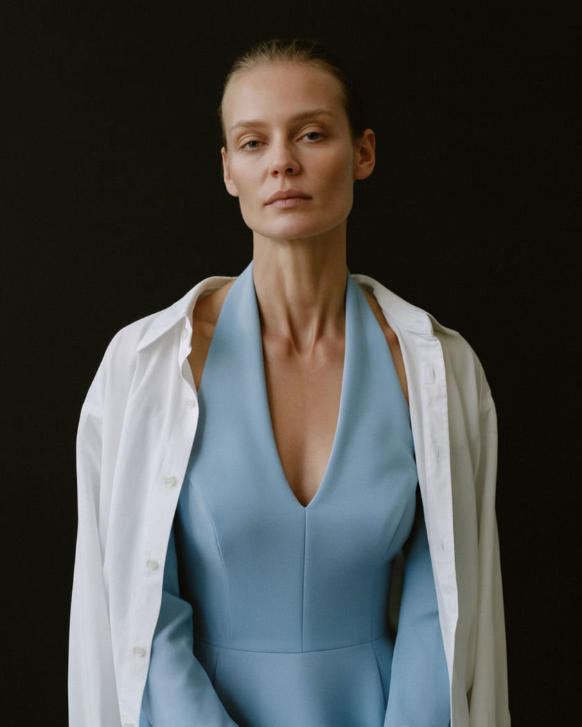 A portrait mid-transition, a casual outfit resolving into a tailored halter top on a soft studio backdrop