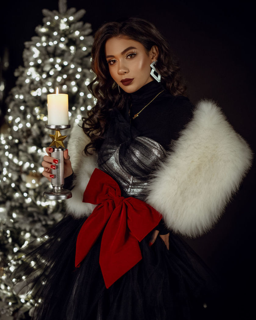 An elegant Christmas portrait in rich festive wardrobe lit by candlelight beside a softly glowing tree