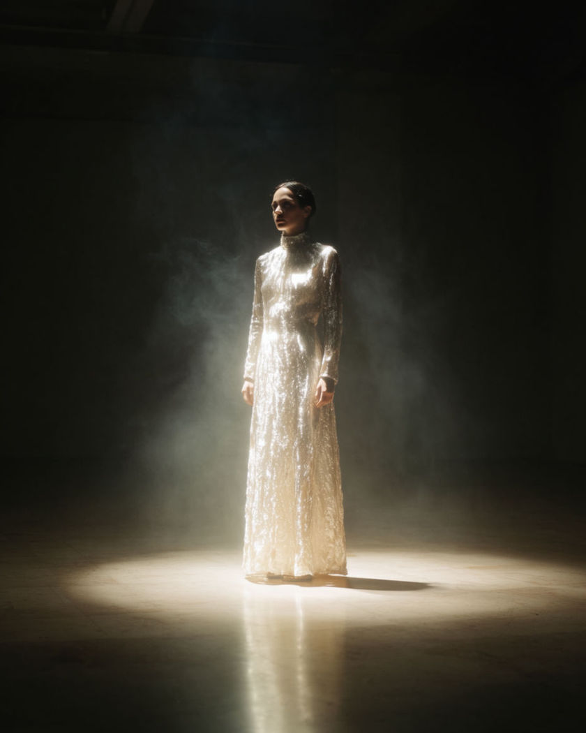 A figure isolated by a single spotlight as the room around them fades into total darkness
