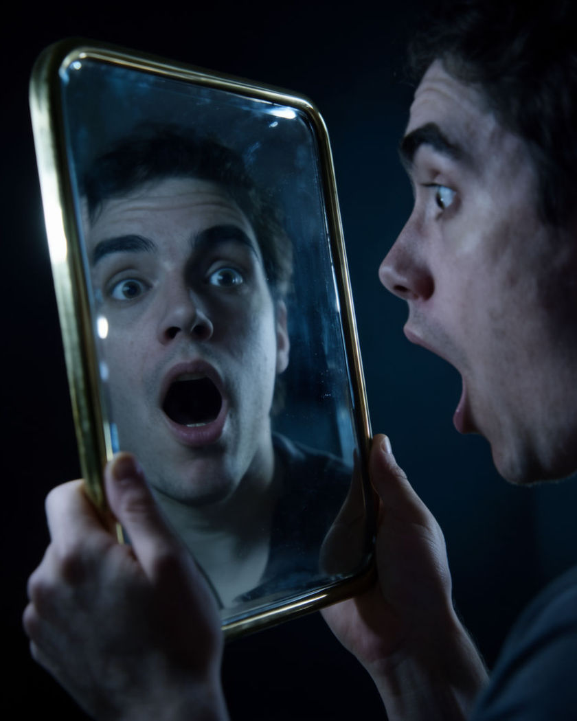 A person recoiling in shock as their mirror reflection swaps gender in one sudden instant