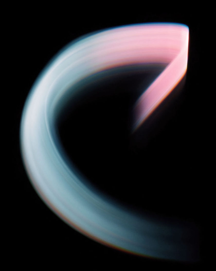 A luminous curved flight path arcing over dark ridgelines, one banking sweep of light against a pure black ground
