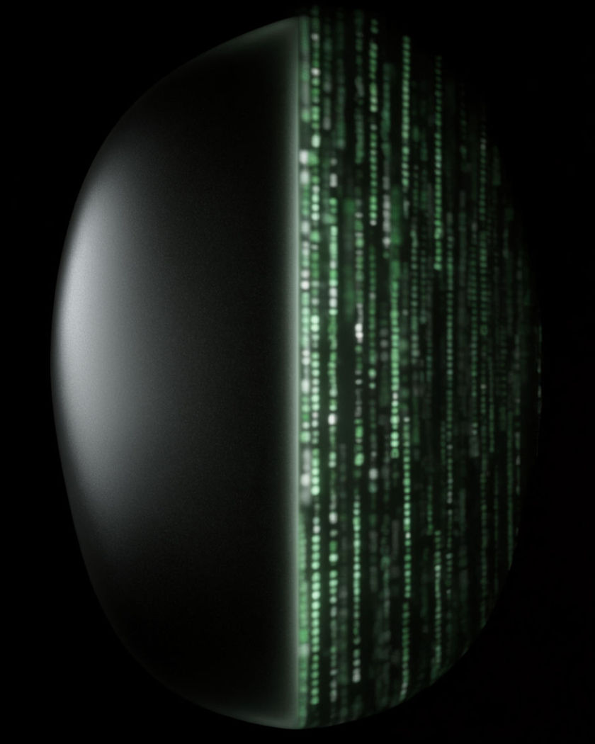 A vertical seam of light where the left half is a smooth dark curved surface catching a on a black ground