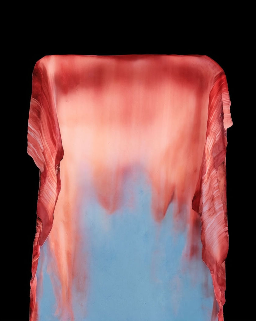A wall of colour sagging and dripping downward to expose a different colour beneath it against a pure black ground