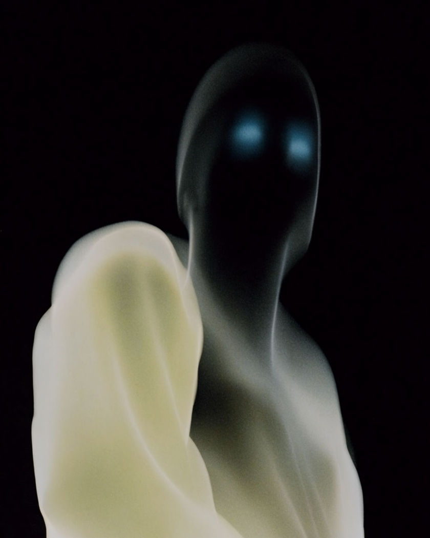 A tall shadowed silhouette with faint glowing eyes rising behind a soft foreground shape against a pure black ground