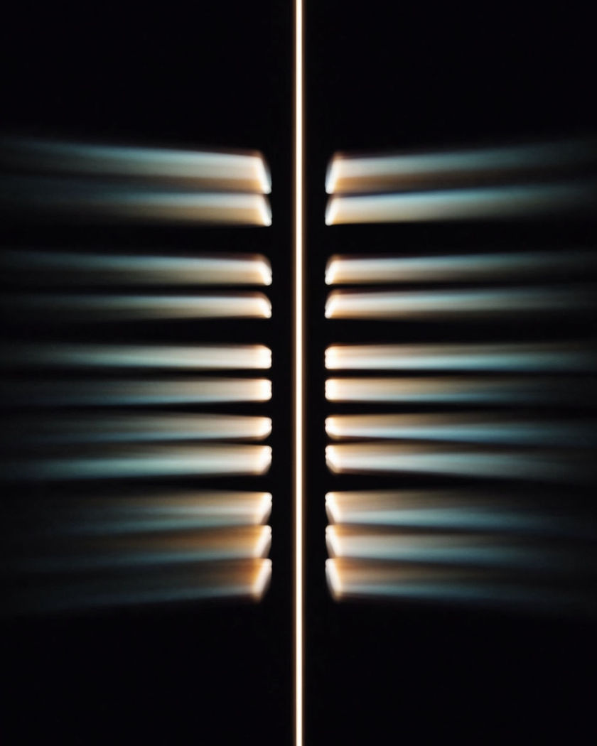One vertical ribbon of light held sharp while the ribbons beside it smear sideways into motion blur