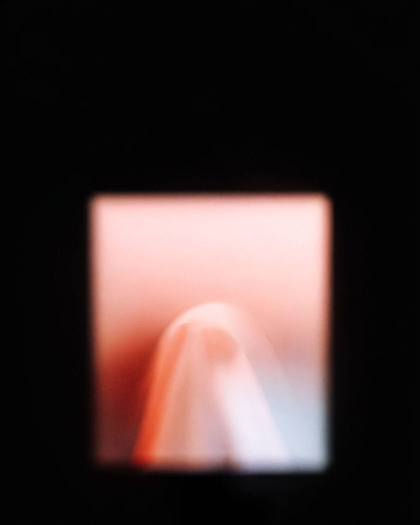 A bright rectangle of light with a glowing form appearing to push forward out of its surface against a pure black ground