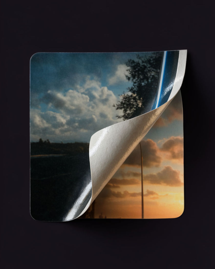 A paper sticker layer curling up from one corner, revealing a different image underneath