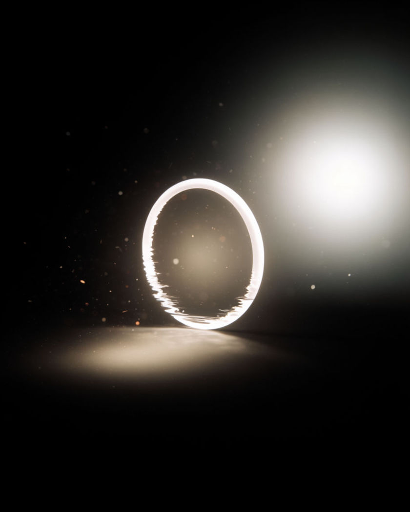 A single thin ring of white light standing upright in empty black space on a black ground