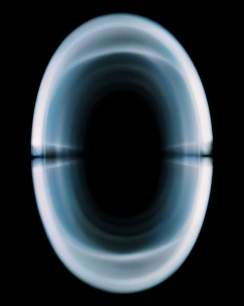A glowing vertical ring of blue light opening into deep space against a black ground
