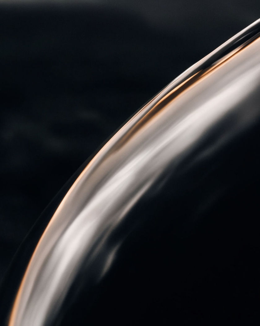 A sleek silver fuselage curve catching warm rim light against a black ground