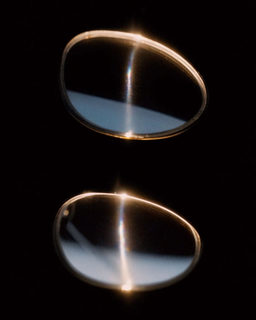 Two dark lens shapes floating side by side in black space on a black ground