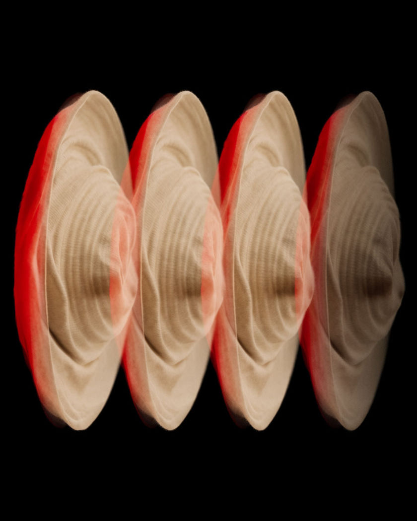 A single spinning translucent form in black space captured as four frozen positions in on a black ground
