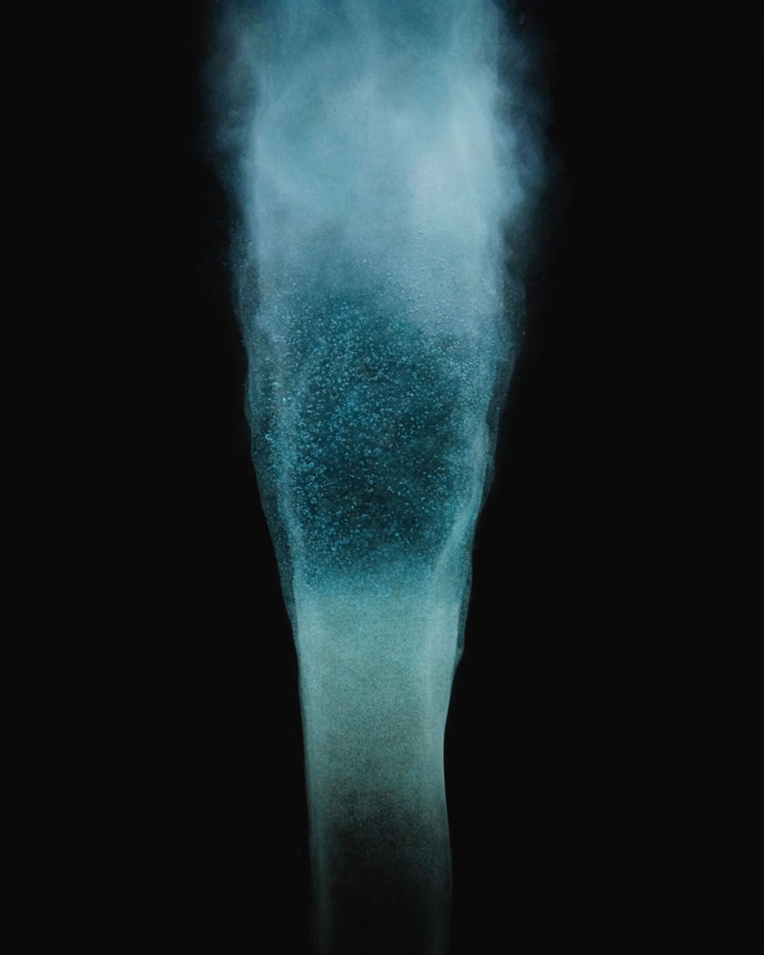 A soft blue column of light and rising bubbles cutting upward through deep water above a pure black ground, no text