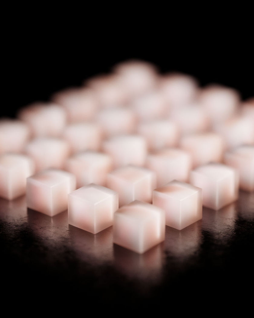 Rows of small luminous cubes arranged like a toy town on a black tabletop on a black ground